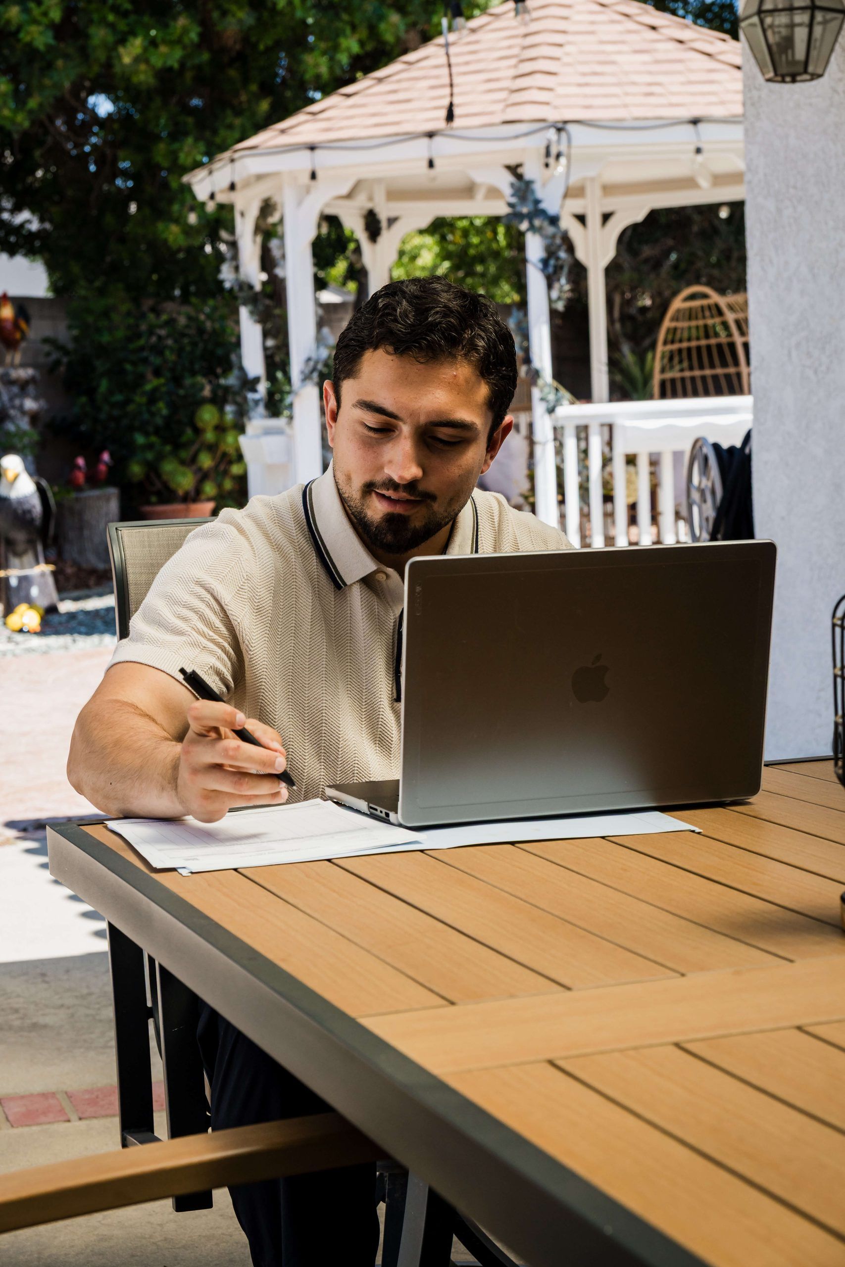 Roberto Valadez writing at a backyard table in Santa Maria