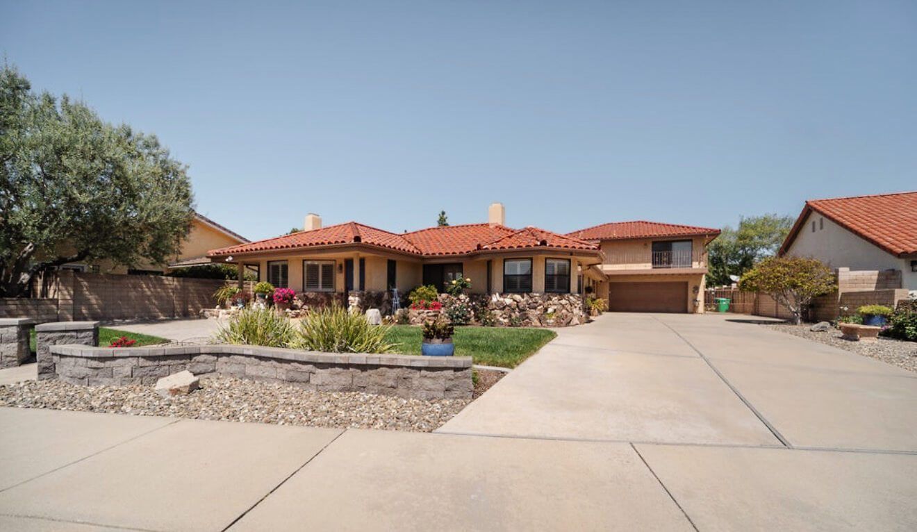 A single-story tile-roof home with a long driveway