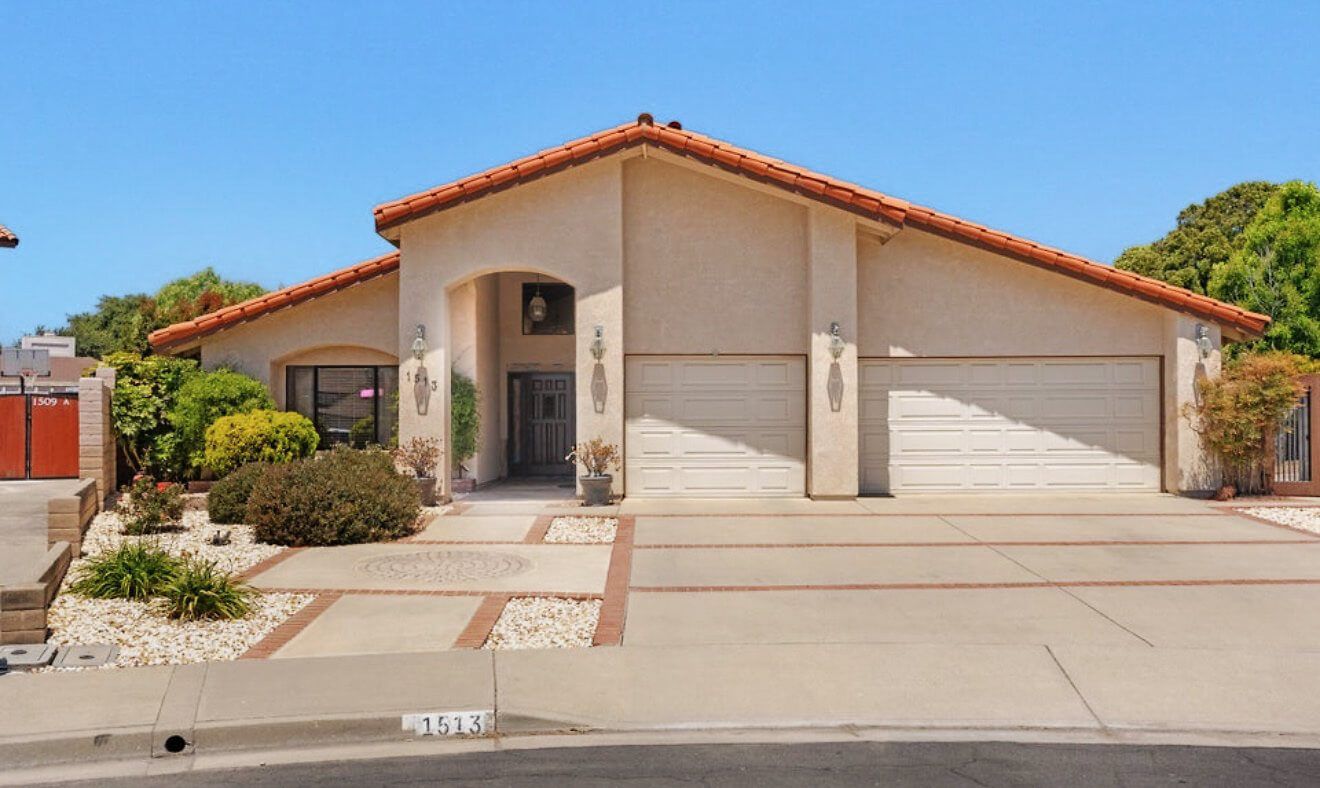 A stucco home with a tile roof and an arched entry