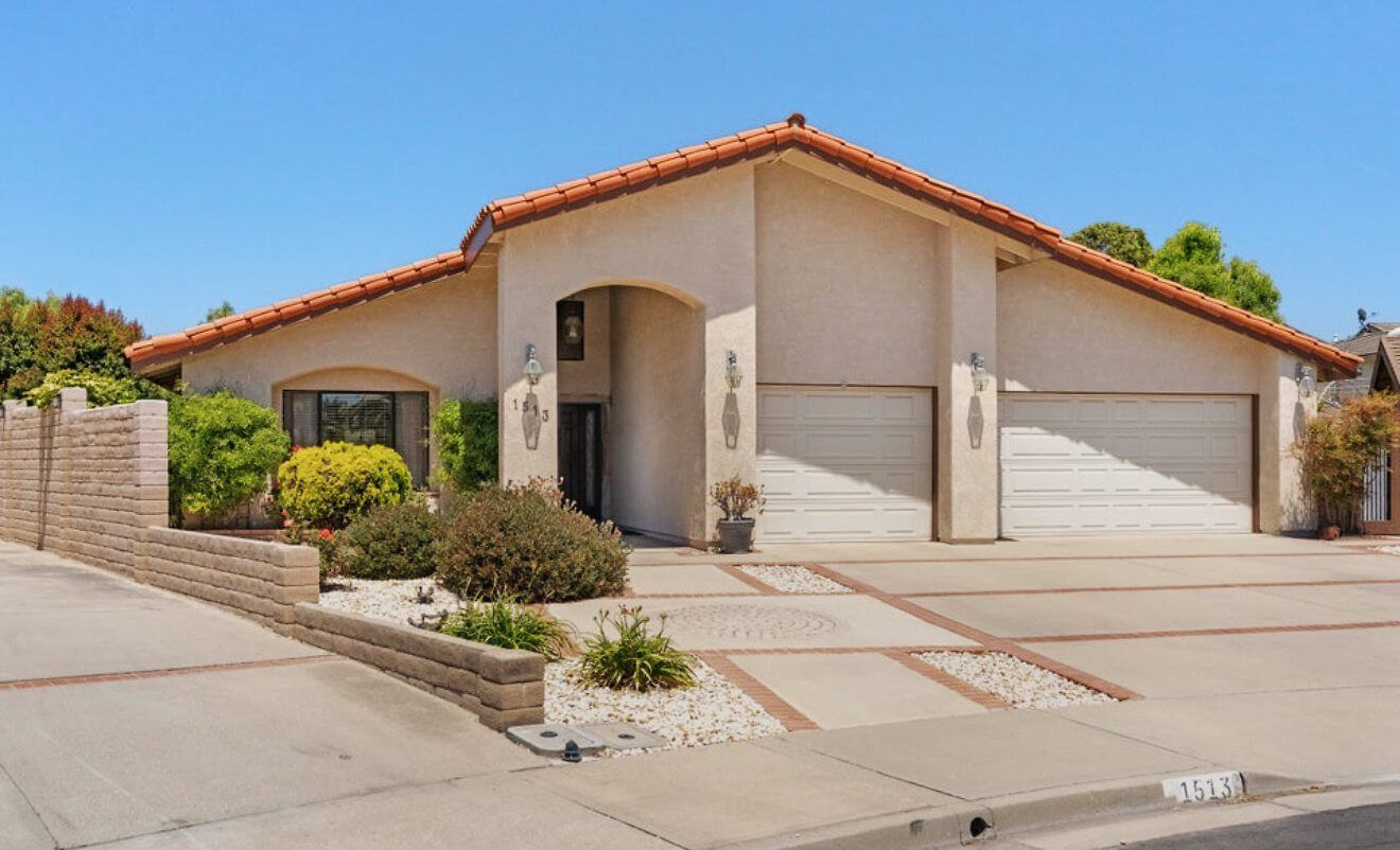 A single-story home with a tile roof and a long driveway