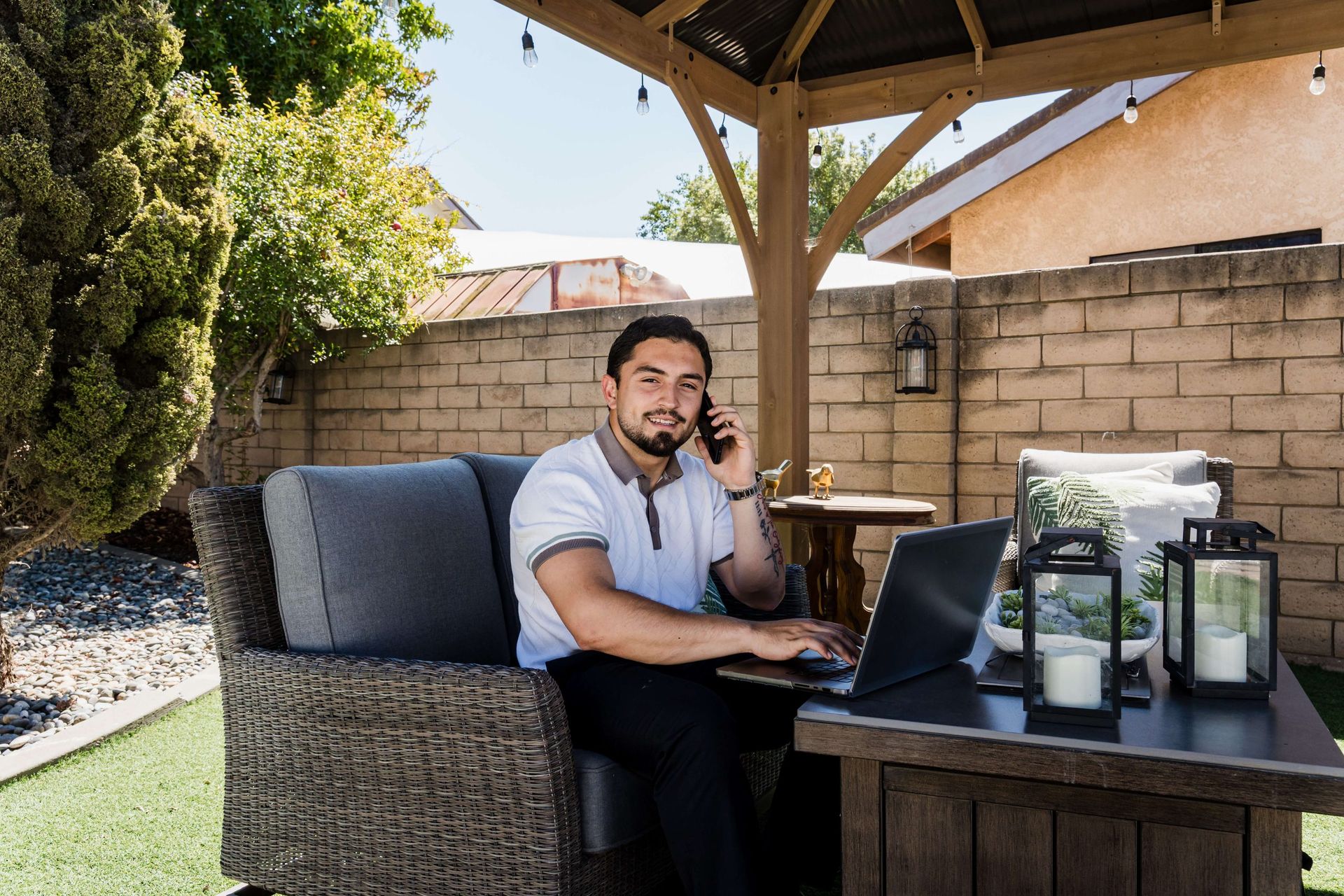 Roberto Valadez on the phone with his laptop at a backyard table in Santa Maria