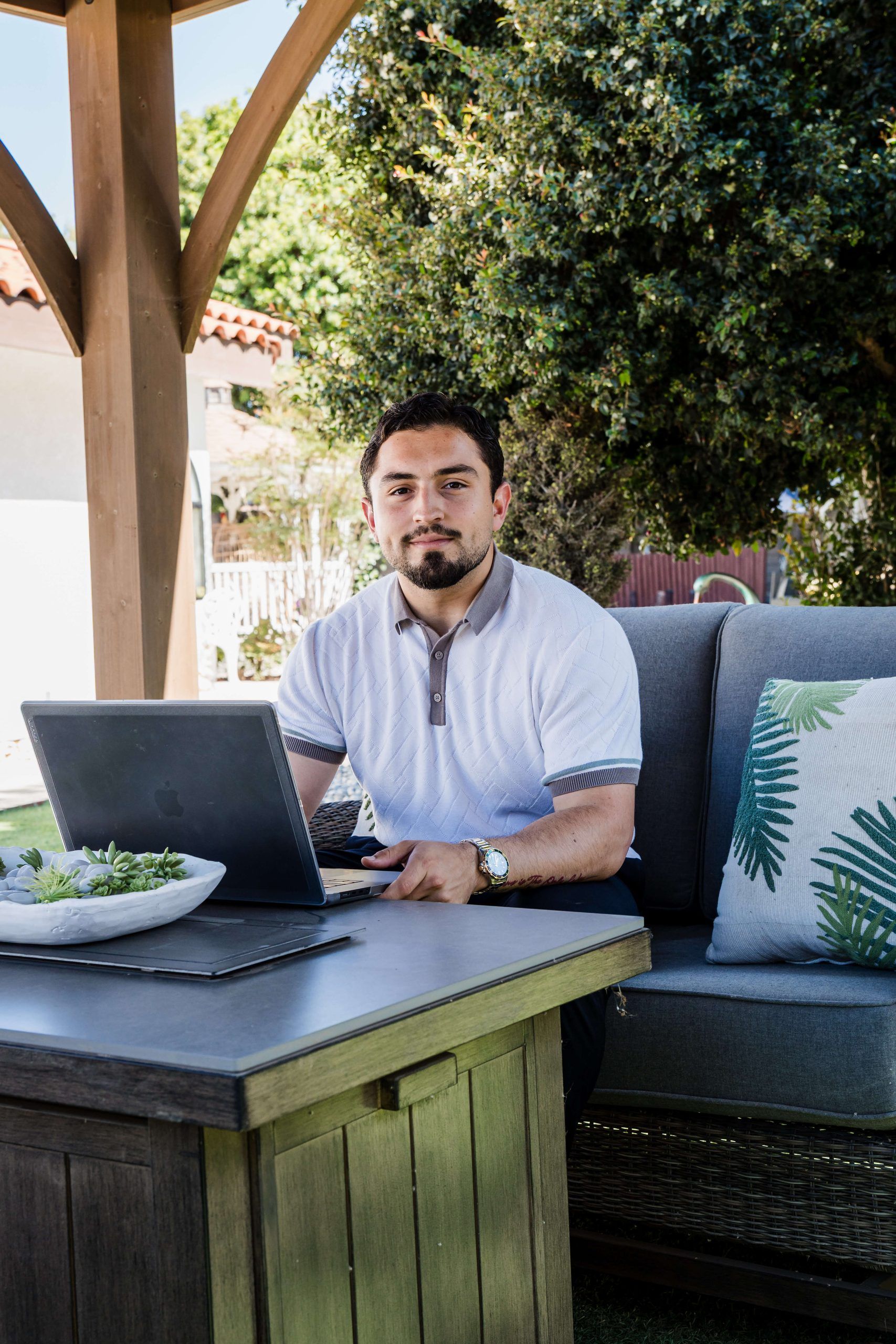 Roberto Valadez at his desk on the patio, looking at the camera