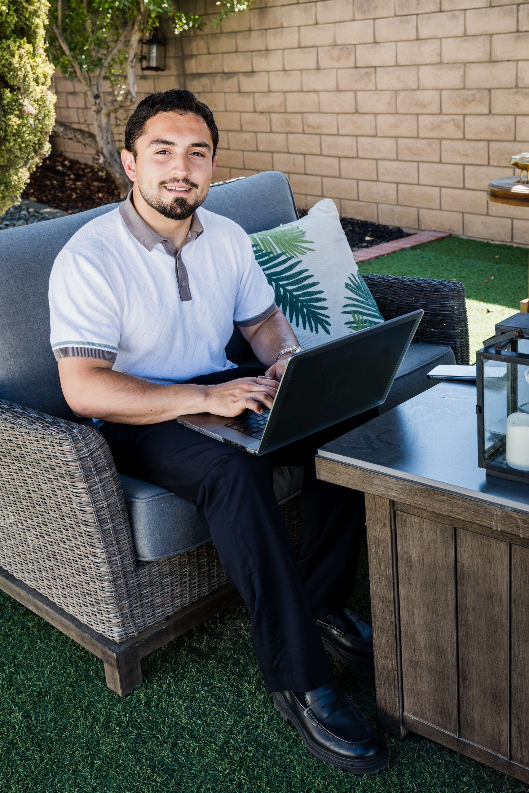 Roberto smiling at his laptop on the sofa